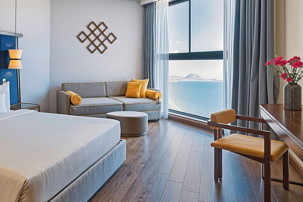 Een moderne hotelkamer met een groot bed, een slaapbank, een bureau en uitzicht op zee.