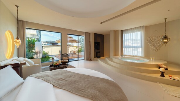 A modern hotel room with a large bed, a sitting area with a view, and a separate bathroom with a jacuzzi. - Warm Shore (Chengdu)