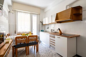 Een keuken met witte kasten, een houten aanrecht en een eethoek met een tafel en stoelen.