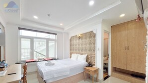 Habitación de hotel con una cama grande, un escritorio con silla, un armario y ventana con vistas al exterior.