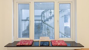Una ventana con tres cristales, un banco de madera y dos cojines rojos.