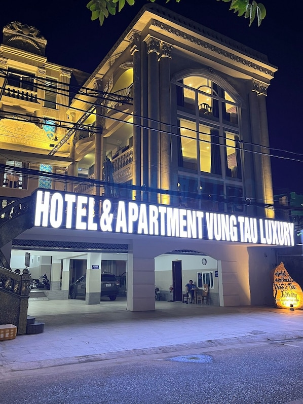 A hotel with a prominent sign reading "HOTEL & APARTMENT VUNG TAU LUXURY".