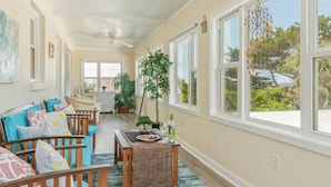 Una habitación iluminada por el sol con un banco de madera, una mesa de comedor y vistas al exterior con vegetación.