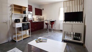 A compact kitchen with a microwave, a small refrigerator, and a dining area with a table and two chairs.