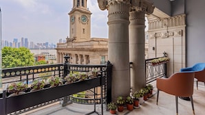 Een balkon met uitzicht op een historisch gebouw, inclusief een klokkentoren, en een stadshemelbeeld.