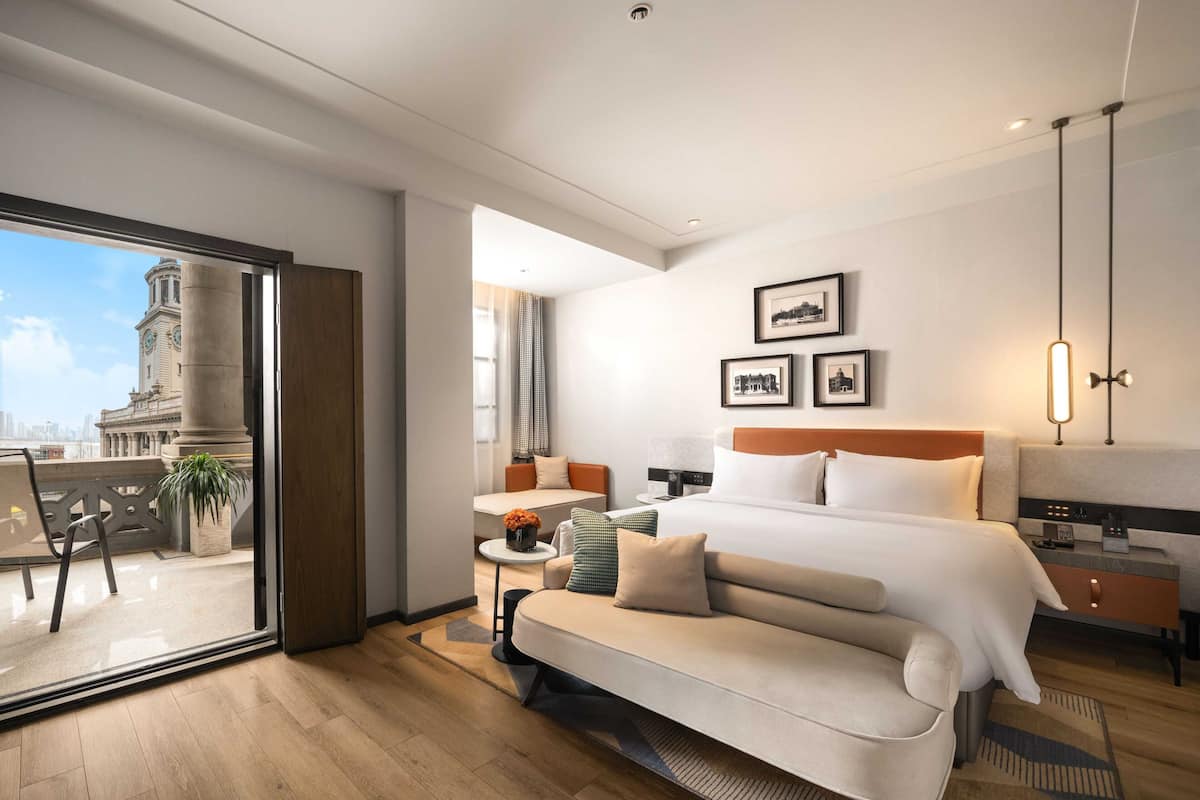 Ett modernt hotellrum med en stor säng, en soffa, ett skrivbord och utsikt över stadsbilden.
