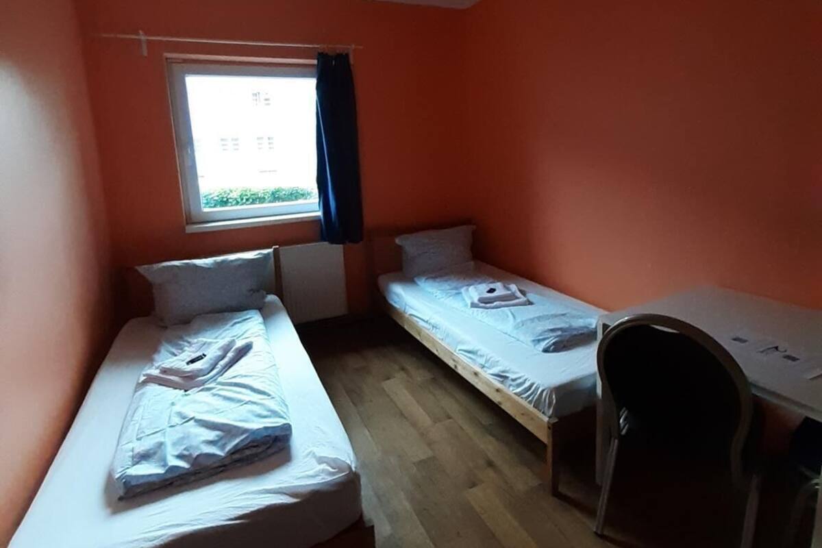 Een slaapzaal met twee eenpersoonsbedden, een bureau en een raam met gordijnen.