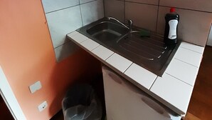Une cuisine compacte équipée d’un évier, d’un four à micro-ondes et d’un petit réfrigérateur.