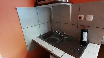 Eine kleine Küche mit Spüle, Mikrowelle und einem Kühlschrank.