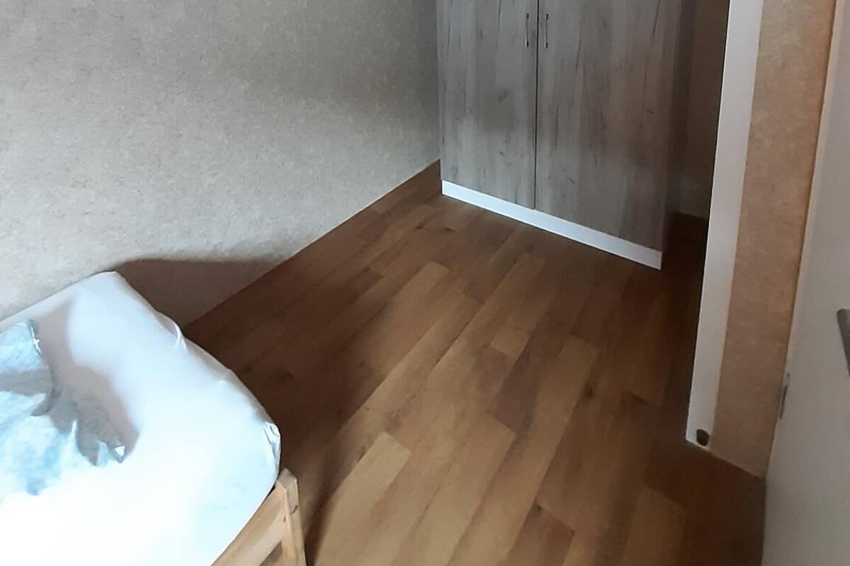 Een kamer met een bed, een kledingkast en een houten vloer.