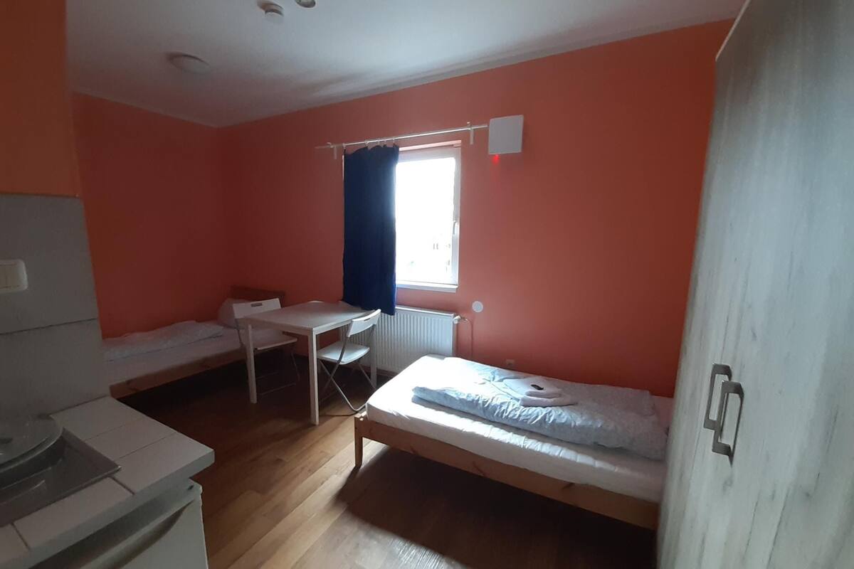 Een studentenkamer met een bed, een bureau en een stoel.