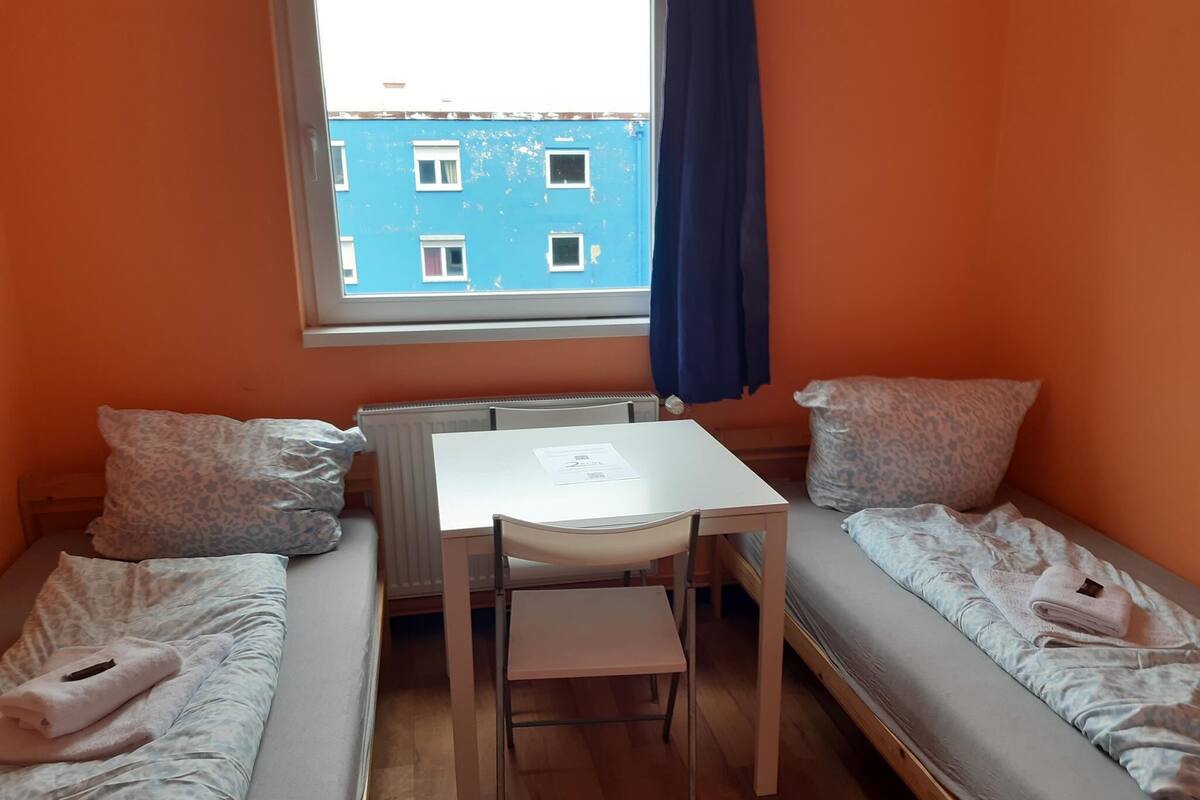 Una habitación pequeña con cama, una mesa y una ventana.