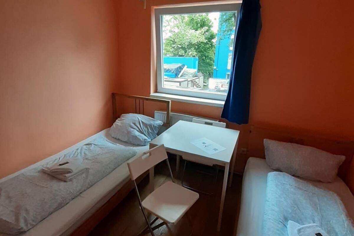 Een kleine kamer met twee eenpersoonsbedden, een bureau en een raam.