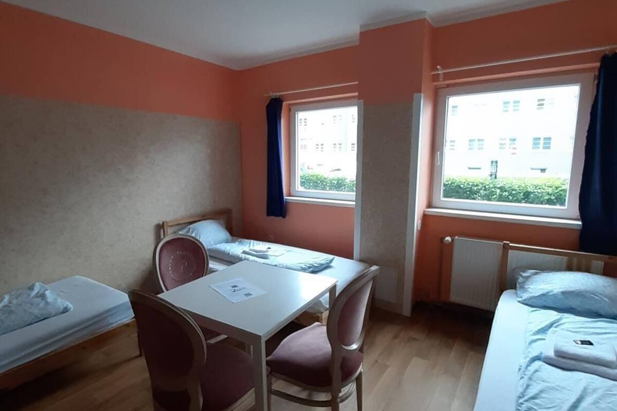 Een studentenkamer met twee eenpersoonsbedden, een tafeltje en stoelen.