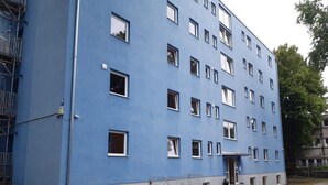 A multi-story building with a blue exterior, multiple windows, and a gated entrance. - 2-Rent Group Hostel Rooms&Apartments TUB19A (Munich)