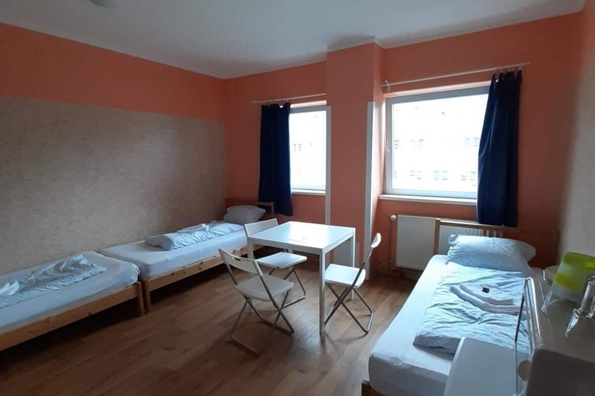 Une chambre de dortoir avec deux lits simples, une petite table et une chaise.