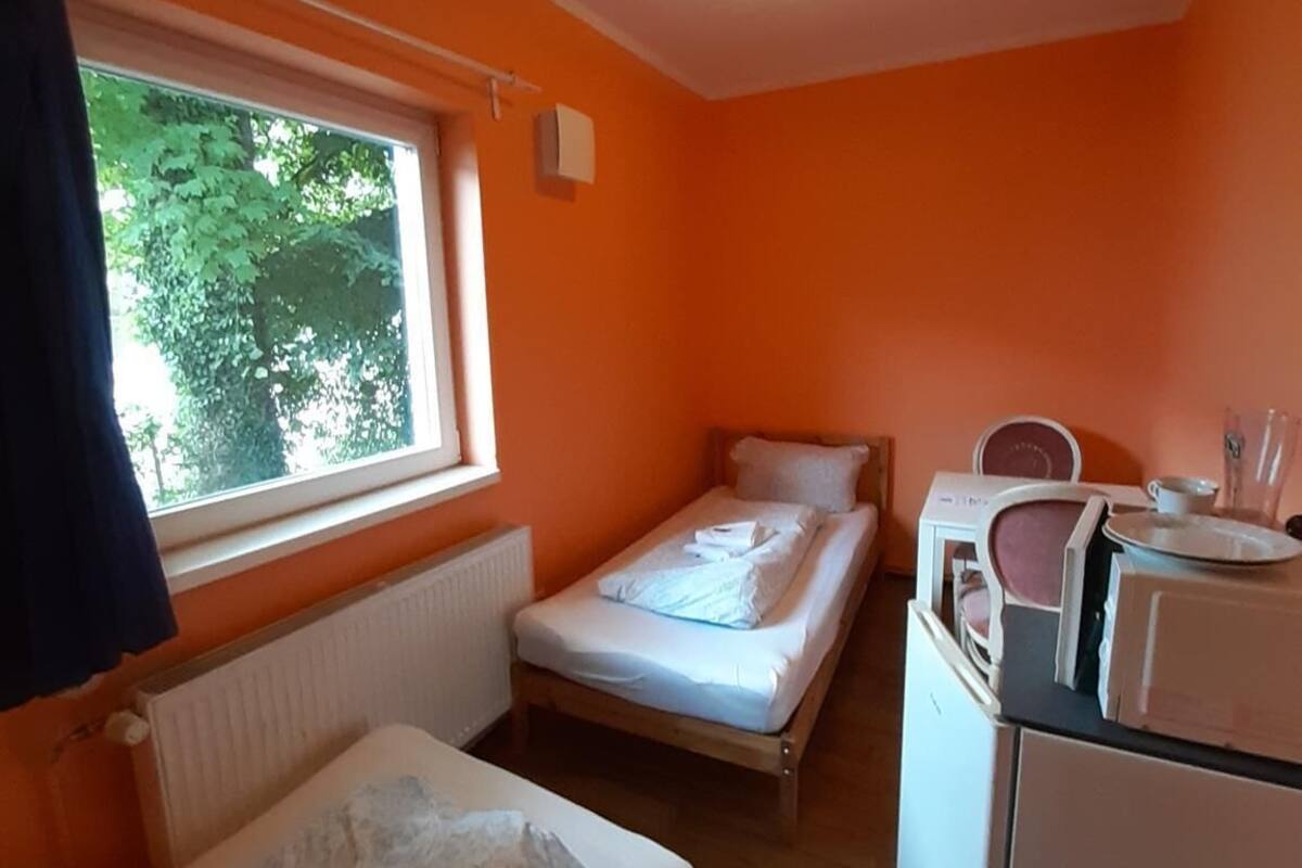 Een compacte kamer met twee eenpersoonsbedden, een kleine kitchenette en een raam voor natuurlijk licht.