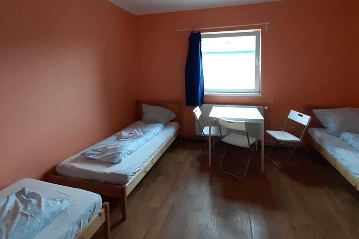 Een studentenkamer met twee eenpersoonsbedden, een bureau en een stoel.