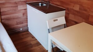 A compact kitchen with a sink, a small refrigerator, and a table. - 2-Rent Group Hostel Rooms&Apartments TUB19A (Munich)