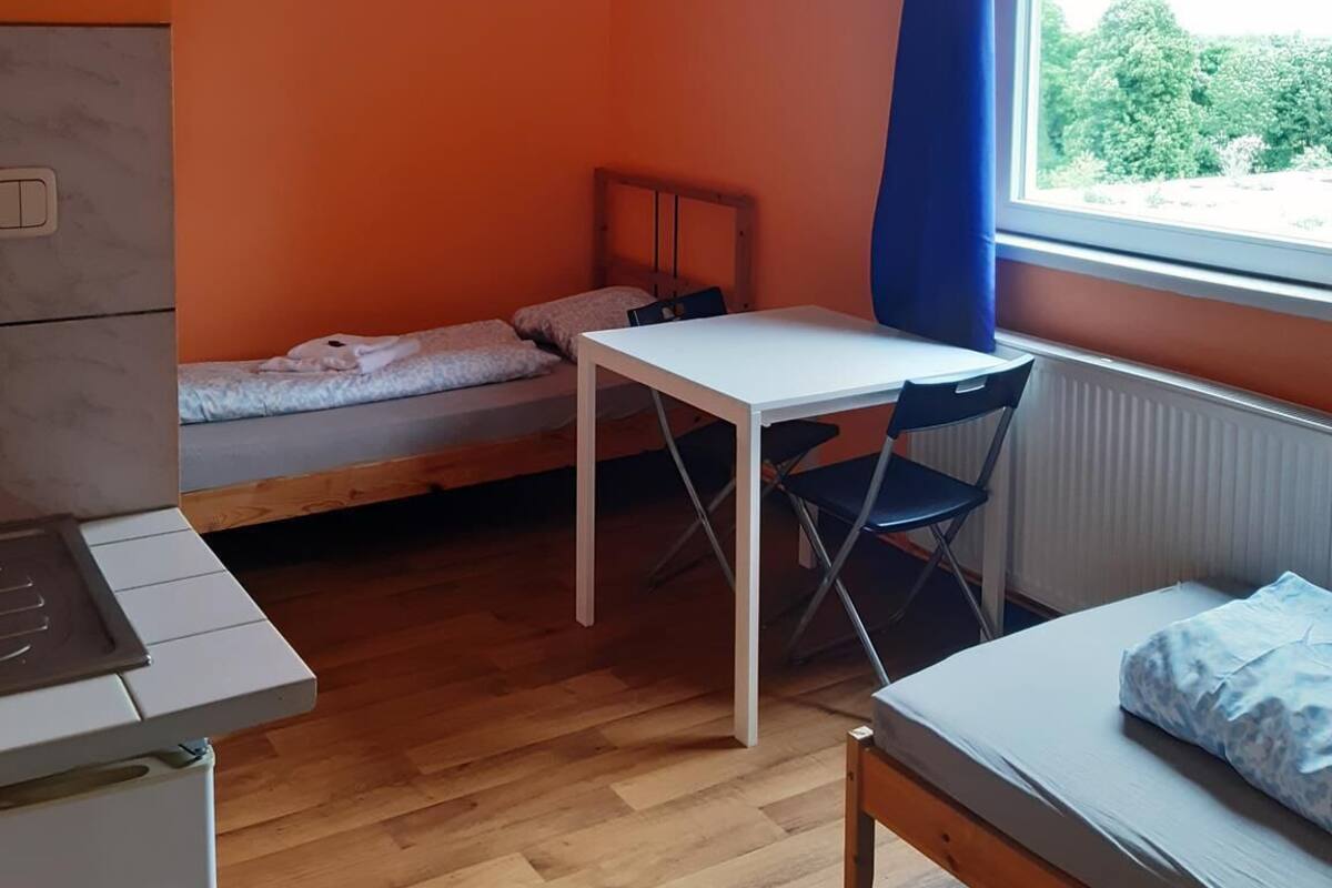 Habitación pequeña con cama, una mesita y ventana.