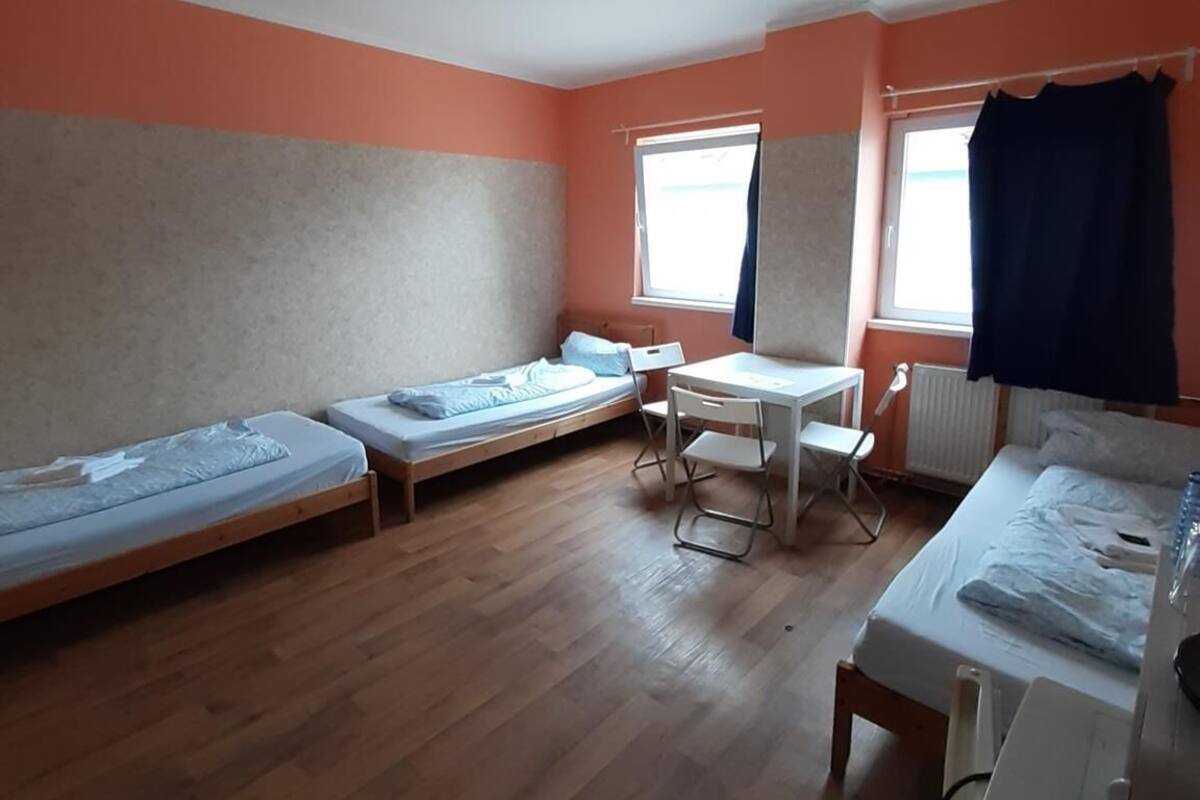 Een slaapzaal met twee eenpersoonsbedden, een tafeltje en een stoel.