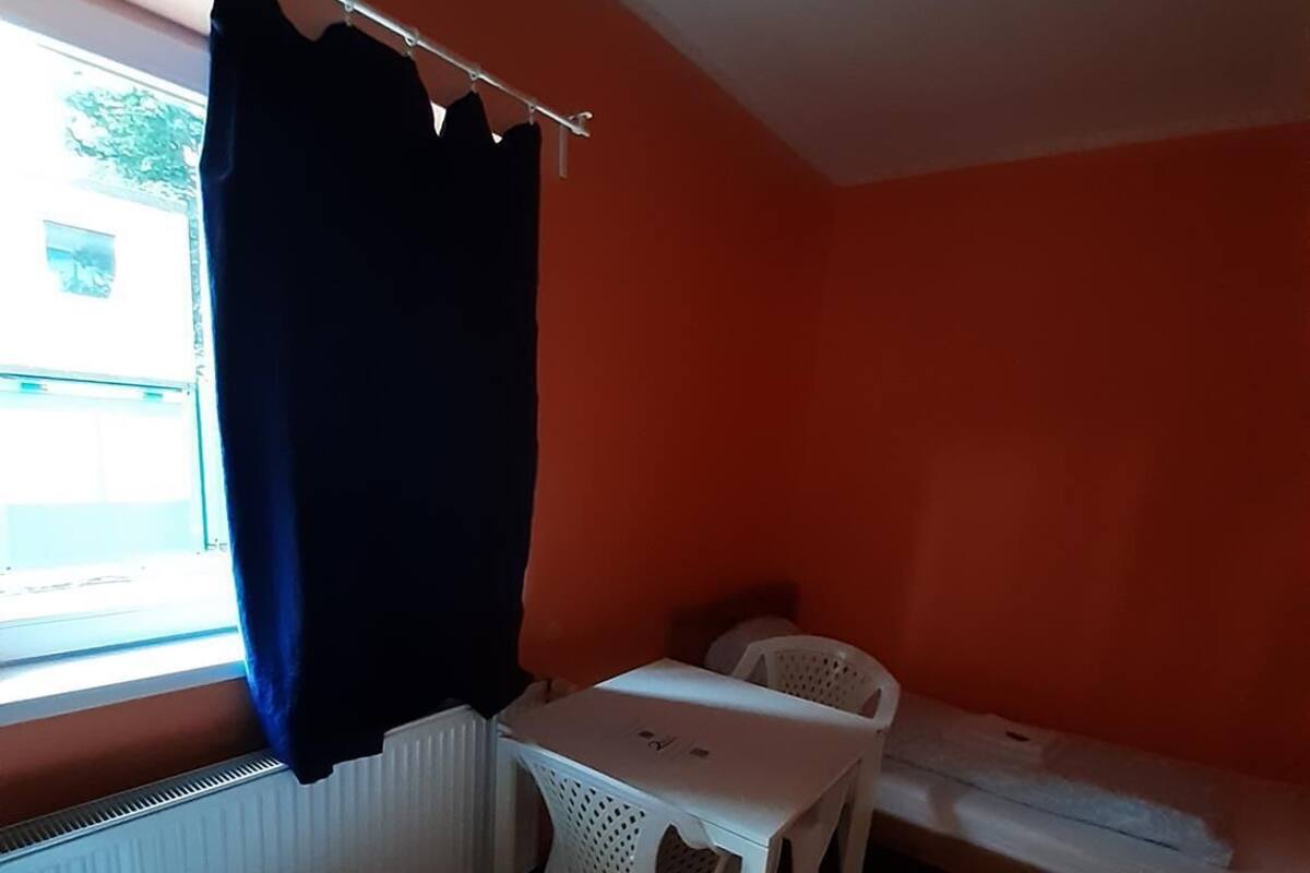Een kleine kamer met een bed, een tafel en een stoel.