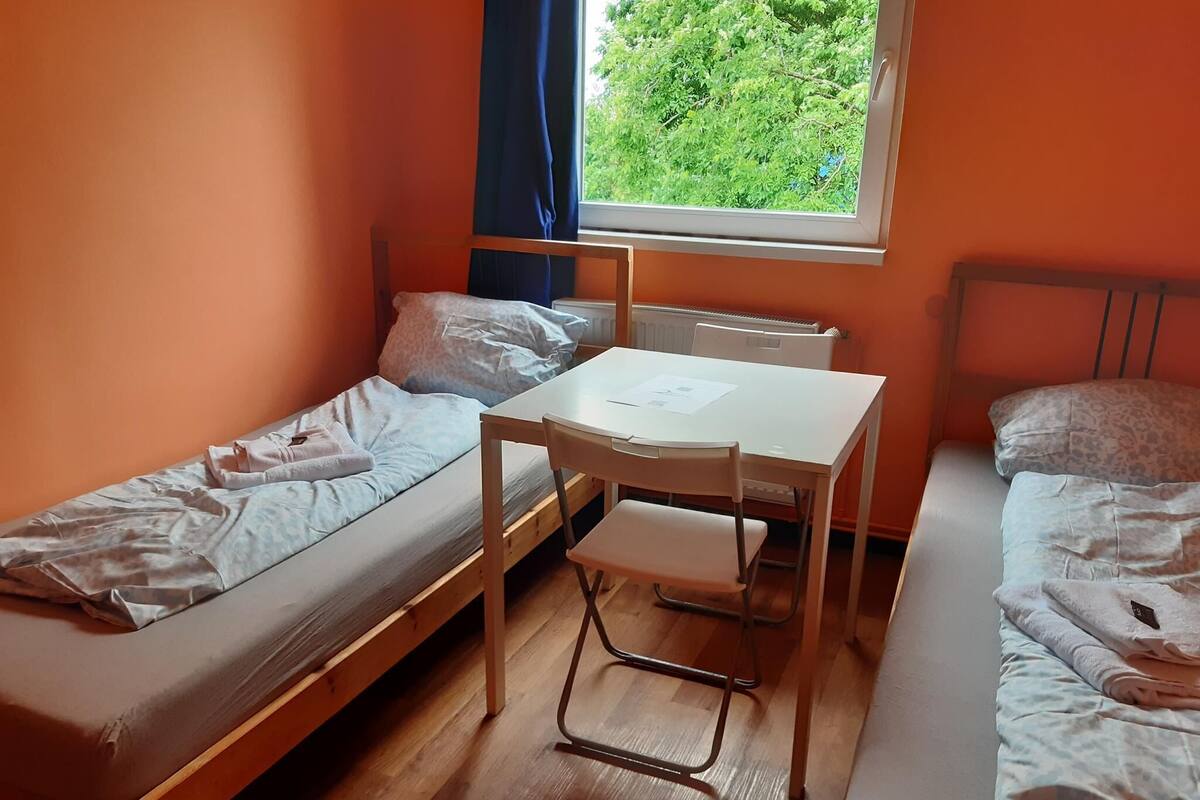 Un dormitorio con dos camas individuales, una mesita y una silla.