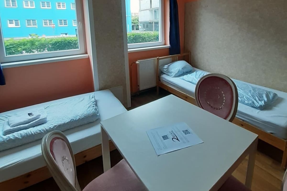 Une chambre de dortoir avec deux lits simples, une table et une chaise.