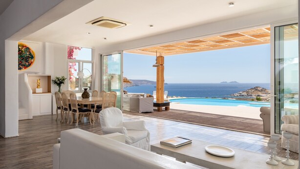 Un interior moderno con comedor, mobiliario blanco y vista al océano.