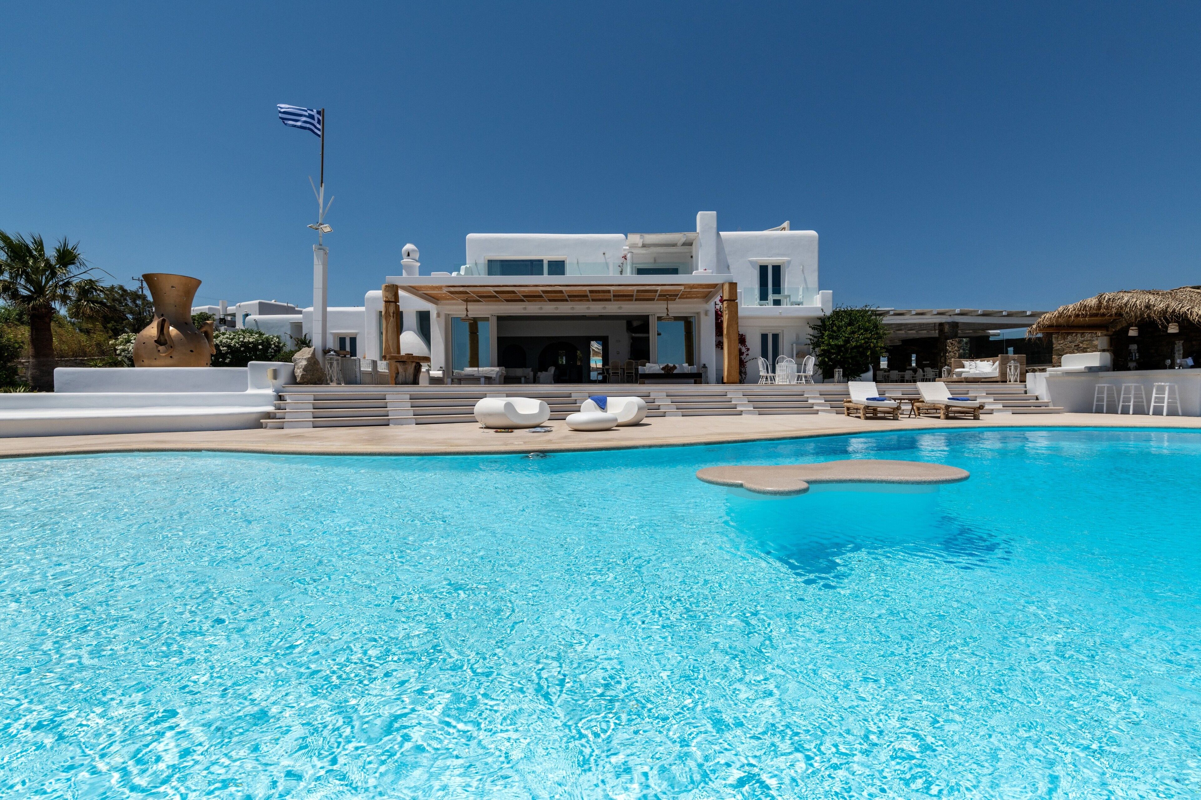 Ein modernes Hotel mit Schwimmbad, Liegestühlen und einer Flagge.