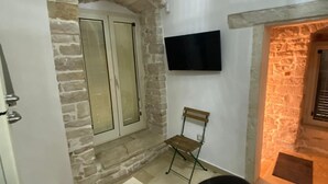 Une pi èce avec une cheminée en pierre, un téléviseur à écran plat fixé au mur, une table à manger avec des chaises et un banc.