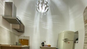 Une cuisine compacte dotée d’un îlot central, d’un luminaire suspendu moderne, d’un réfrigérateur et d’un petit évier.