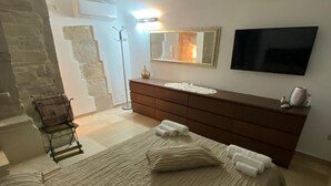 Une chambre à coucher avec un grand lit, une commode, un téléviseur et un escalier menant à l’étage supérieur.