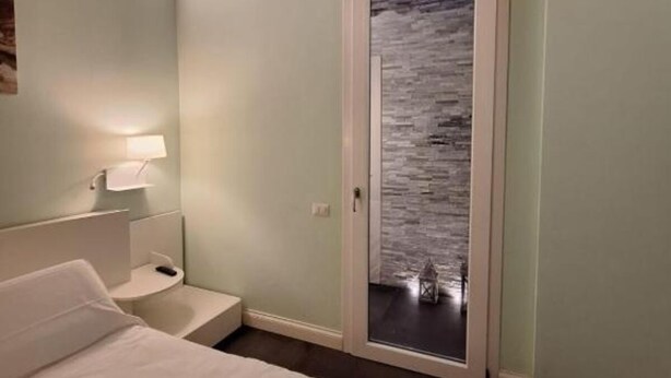 Een slaapkamer met een bed, nachtkastje en een deur naar een balkon.