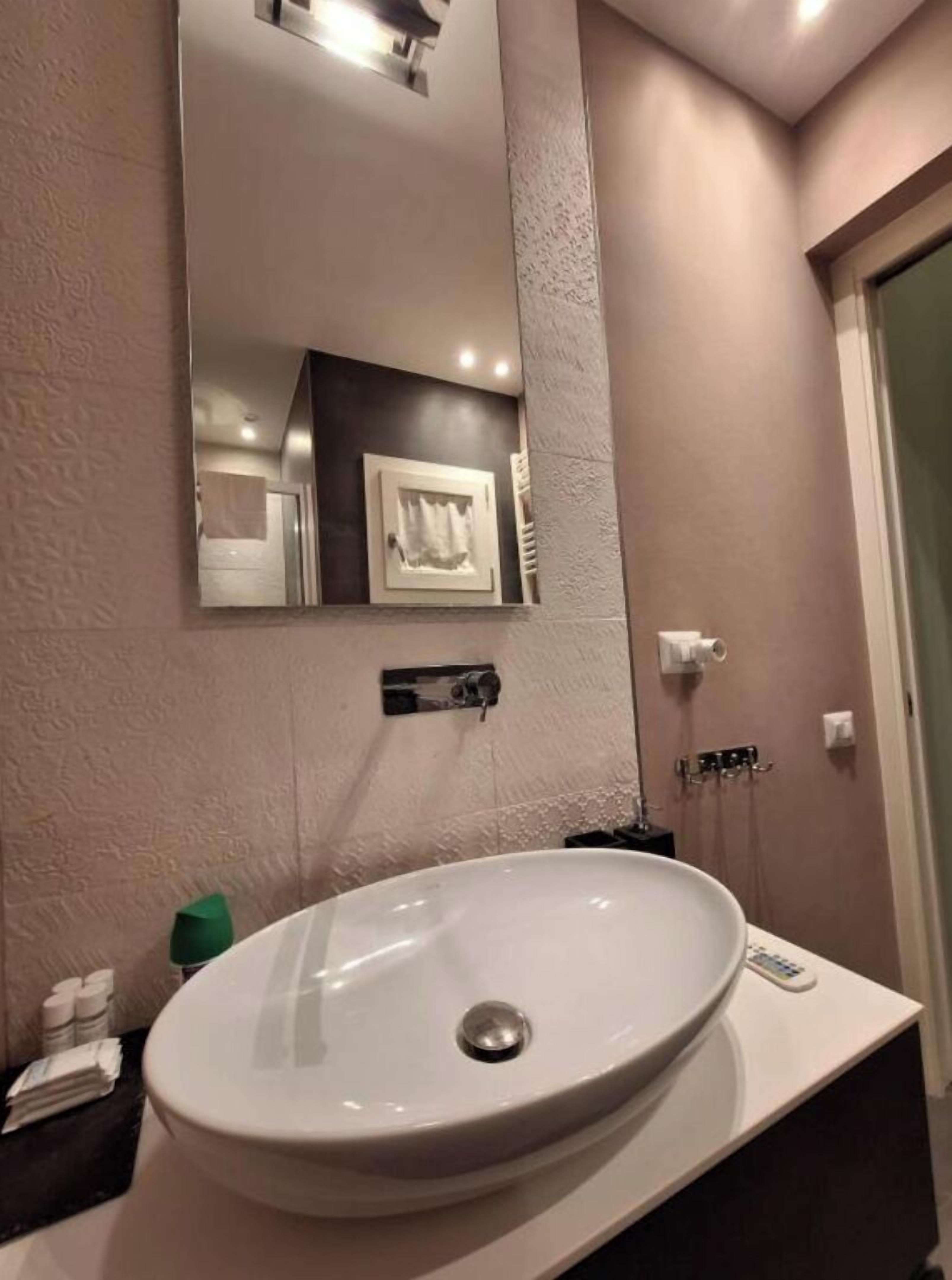 A bathroom with a white sink, a large mirror, and a towel rack.