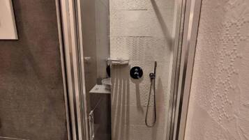 Un baño moderno con ducha acristalada, inodoro y lavamanos.