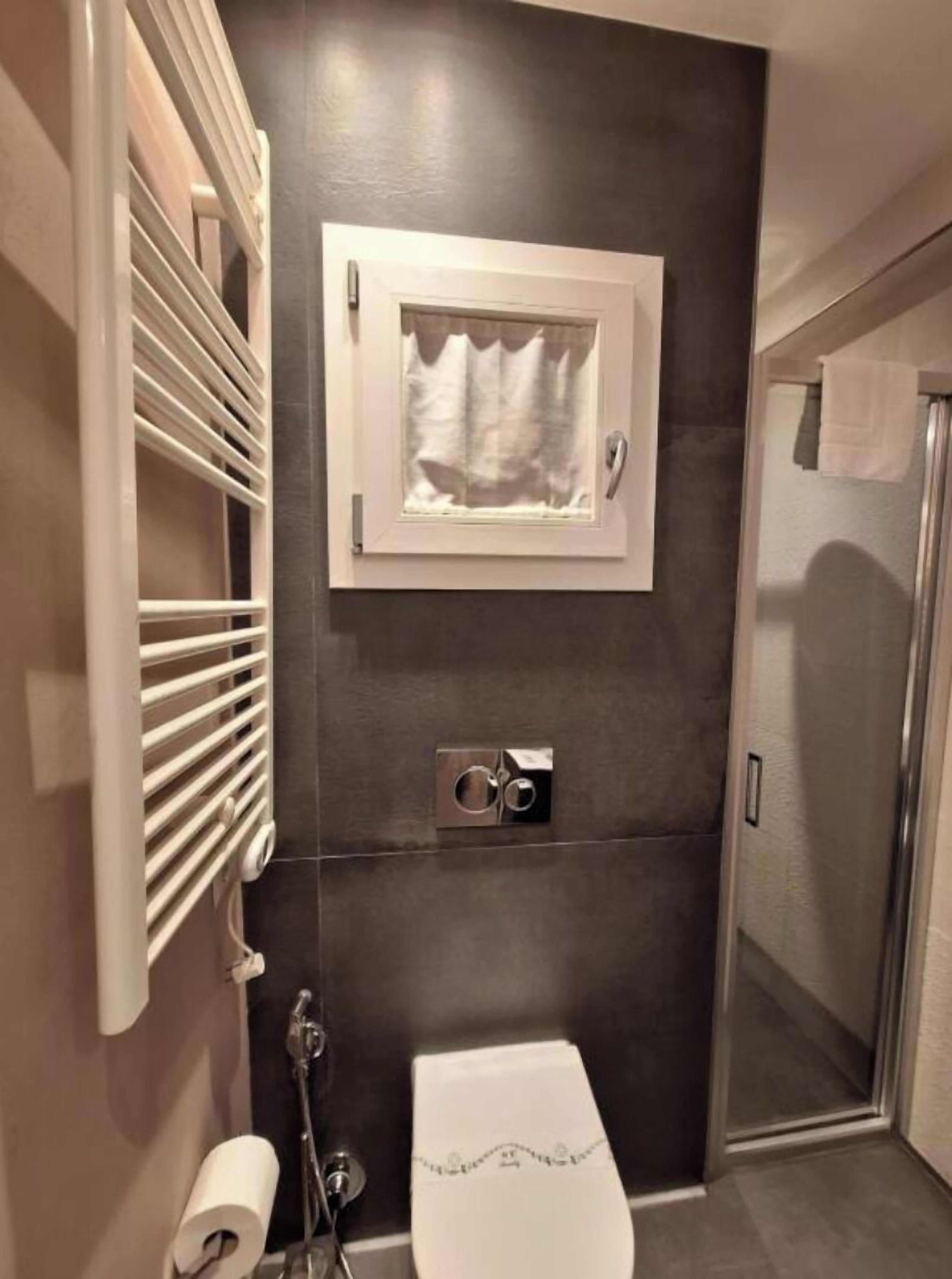 A modern bathroom with a shower, toilet, and towel rack.