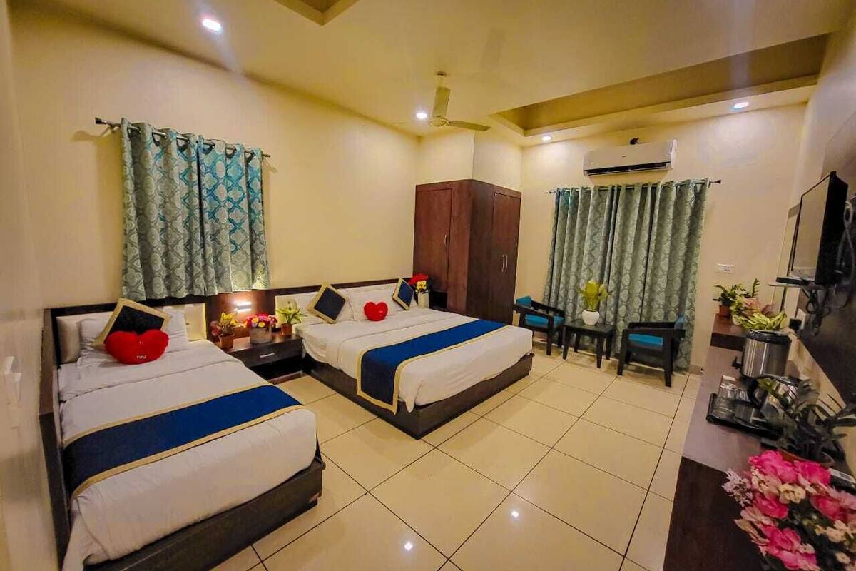 Une chambre d’hôtel avec deux lits, un bureau, une armoire et un téléviseur.
