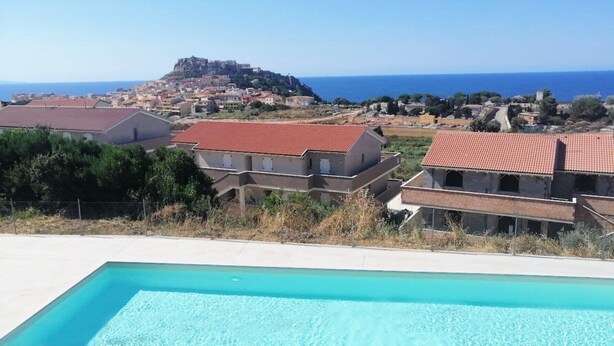 Ein Pool mit Blick auf eine Küstenstadt und eine Burg auf einem Hügel.