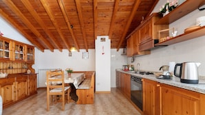 A wooden kitchen with a dining table, cabinets, and a clock on the wall. - Holiday Home 'Vendrogno' with Mountain View, Private Garden and Wi-Fi (Bellano)
