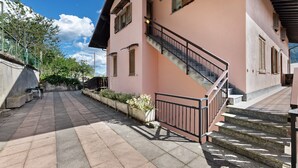 A pink building with a staircase, a paved walkway, and a railing. - Holiday Home 'Vendrogno' with Mountain View, Private Garden and Wi-Fi (Bellano)