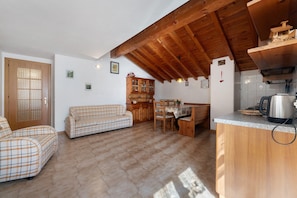 Un accogliente soggiorno con divano, mobiletto in legno e piano cucina.