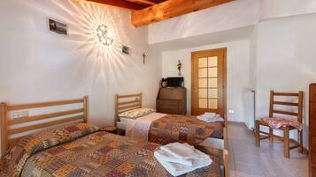 A bedroom with two beds, a wooden ceiling, a radiator, and a wooden chair.