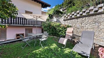 A patio with outdoor furniture, a stone wall, and a pink building with shutters.