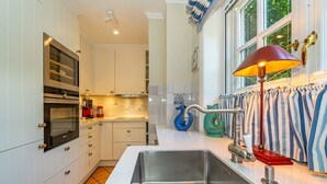 Una cocina moderna con armarios blancos, electrodomésticos de acero inoxidable y un lavamanos grande.