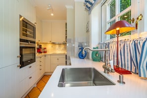 A modern kitchen with white cabinetry, stainless steel appliances, and a large sink. - House Daanshoog - House Daanshoog on Sylt - Comfortable vacation home with sauna, (Sylt)