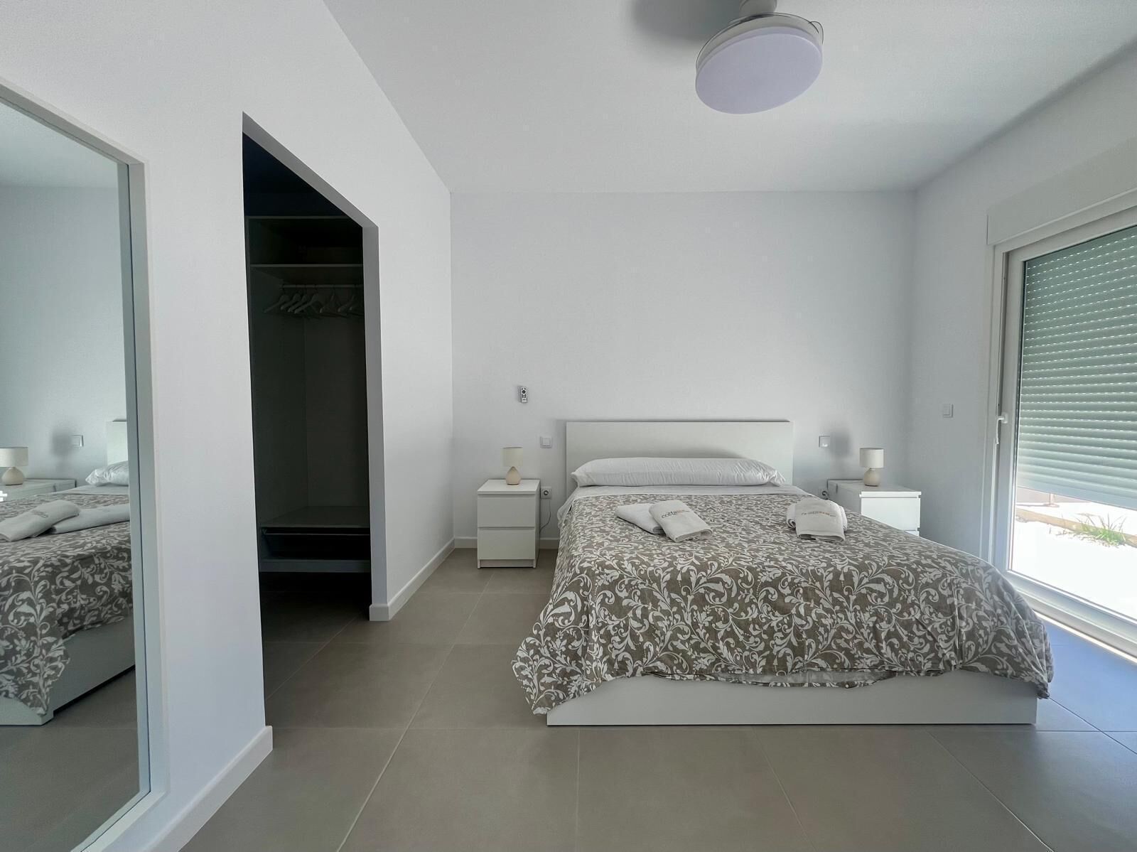Un dormitorio moderno con una cama grande, un vestidor y una ventana con persianas.