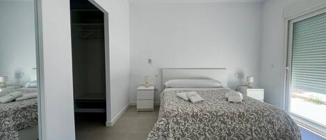 Un dormitorio moderno con una cama grande, un vestidor y una ventana con persianas.