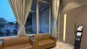 A modern interior with a leather sofa, large windows with curtains, a ceiling fan, and a wall-mounted information kiosk. - O'Nest Pearl (Miraj)