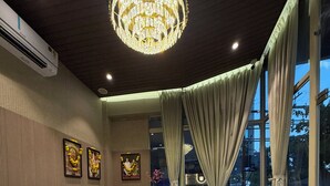 A reception area with a marble counter, a chandelier, framed artwork, and a view through large windows. - O'Nest Pearl (Miraj)